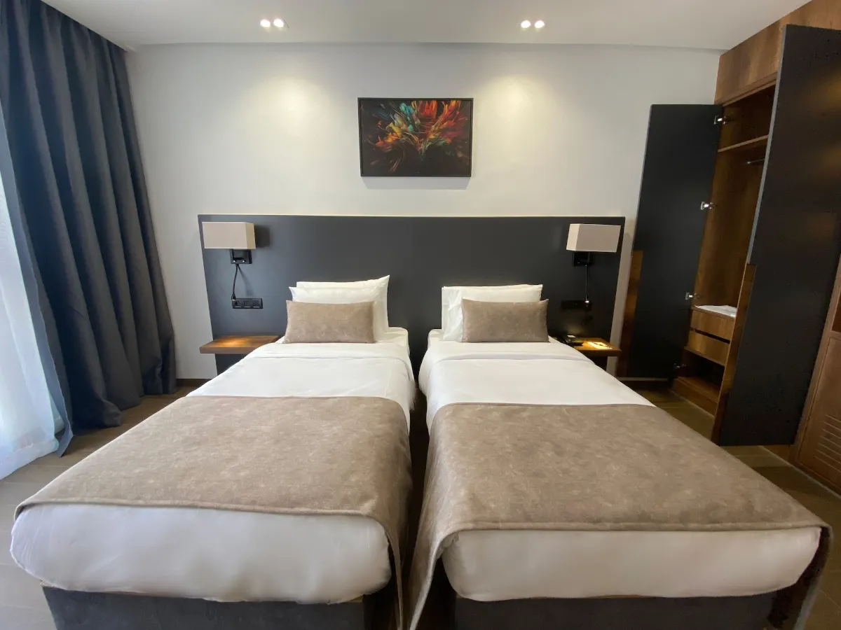 Twin room with two single beds, dark upholstered headboard and wardrobe
